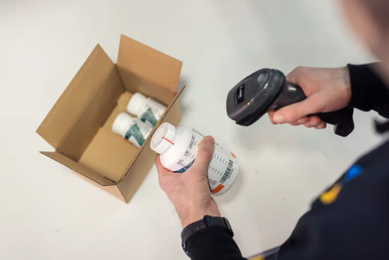 Eine geschlossene Supplement-Dose wird am LCR Packplatz per Barcode geprüft