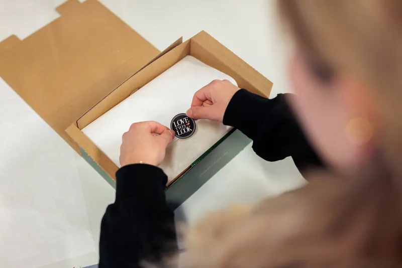 Seidenpapier wird am LCR-Packplatz mit einem LOVE THIS LOOK Markenaufkleber verschlossen