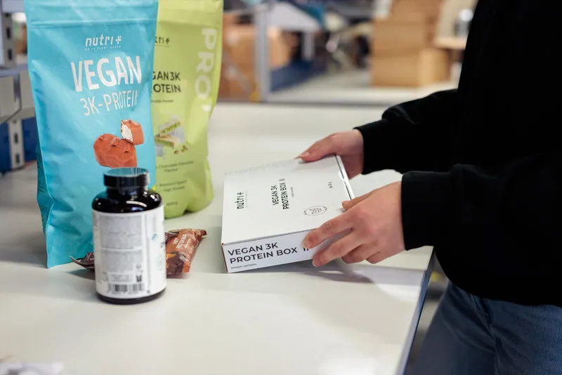 Eine Mitarbeiterin bereitet Produkte und eine Probierbox am LCR Packplatz vor