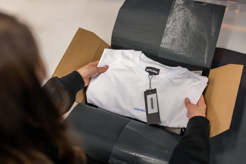 Ein Textil wird bei LCR mit Seidenpapier für den Versand verpackt